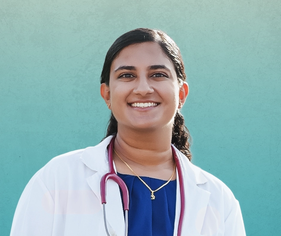 Dr. Coimbatore smiling in a white doctor coat and stethoscope in front of gradient teal background