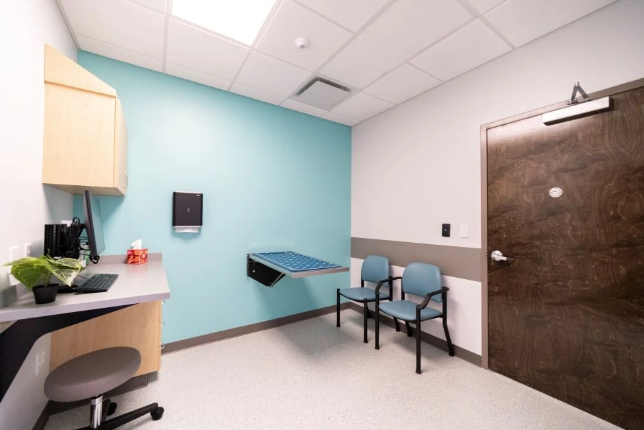Veterinary exam room with teal wall, chairs and metal exam table